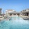 Pool area at our apartments in Midland, TX, featuring pool chairs, reclining chairs, and a clubhouse with shade structure. 