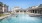 Pool area at our apartments in Midland, TX, featuring pool chairs, reclining chairs, and a clubhouse with shade structure. 