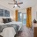 Model bedroom at our apartments in Midland, featuring grey carpets, large windows, and gold curtains. 