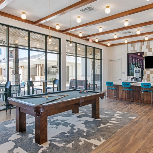 Lounge and dining room at our apartments in Midland, TX, featuring a billiards table, wood grain floor paneling, and seating. Lounge and dining room at our apartments in Midland, TX, featuring a billiards table, wood grain floor paneling, and seating.